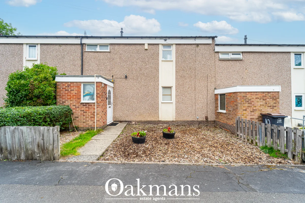 Front-facing terrace house with render walls, brick porch, gravel forecourt, wooden fencing and hedging