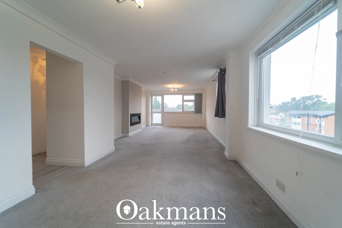 Spacious living room with carpet flooring, white walls, large windows with views over surrounding area, fireplace and mo