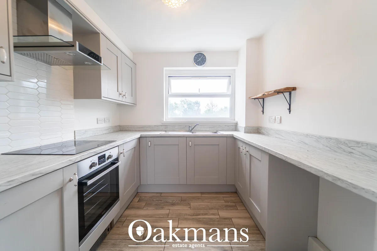 Modern fitted kitchen with grey cabinetry, white hexagon tile splashback, marble worktops, stainless steel appliances an