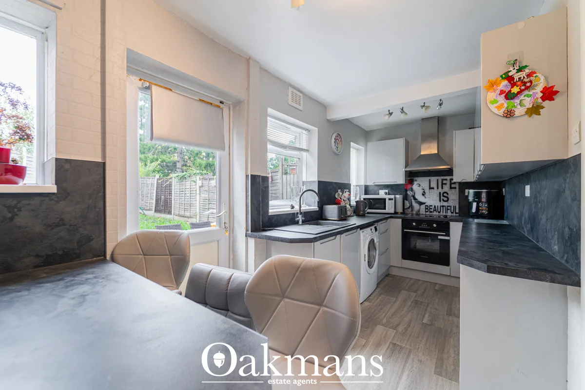 Modern kitchen with white fitted units, black granite worktops, stainless steel appliances, breakfast bar with beige cha