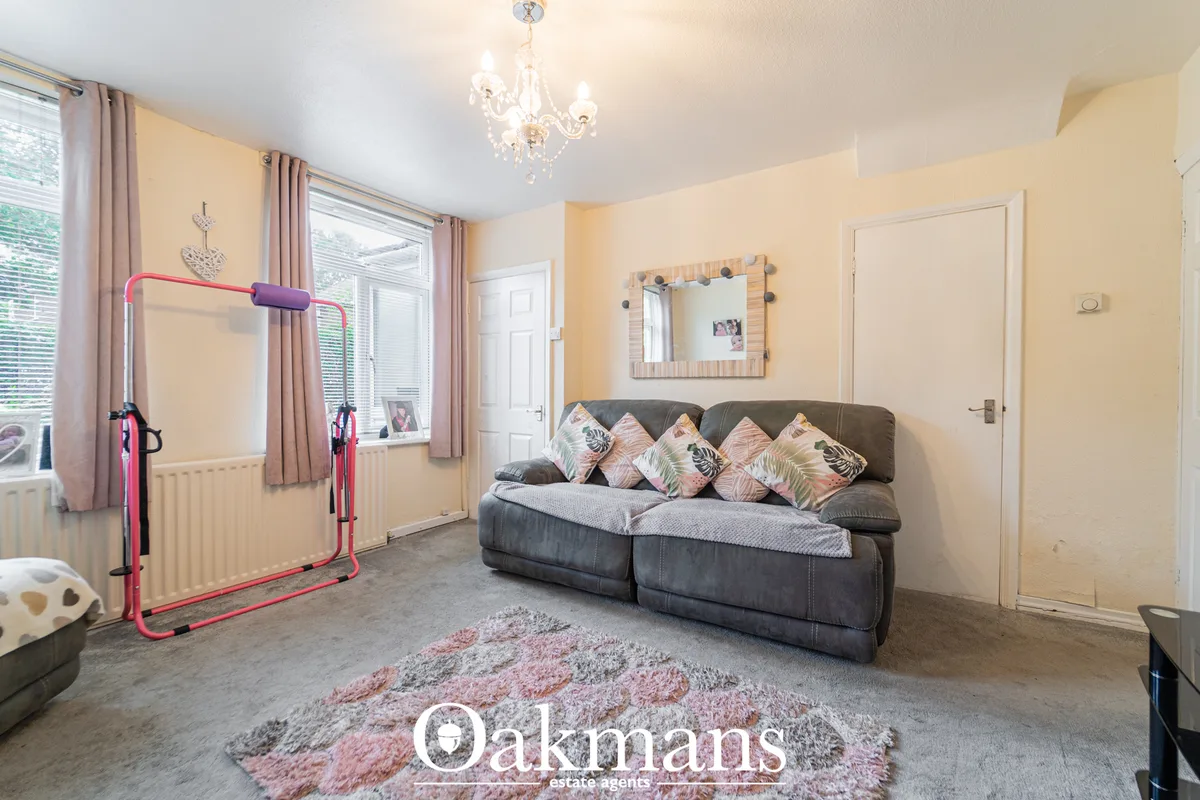 Bright living room with cream walls, gray upholstered sofa with patterned cushions, pink and gray rug, red exercise equi