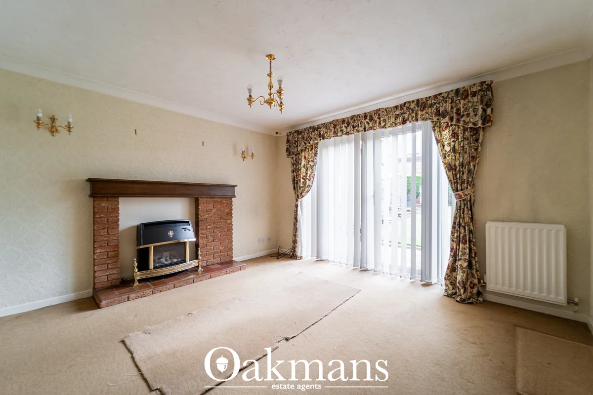 Spacious living room with brick fireplace, gas fire insert, ornate ceiling rose, gold wall sconces, patio doors with pat