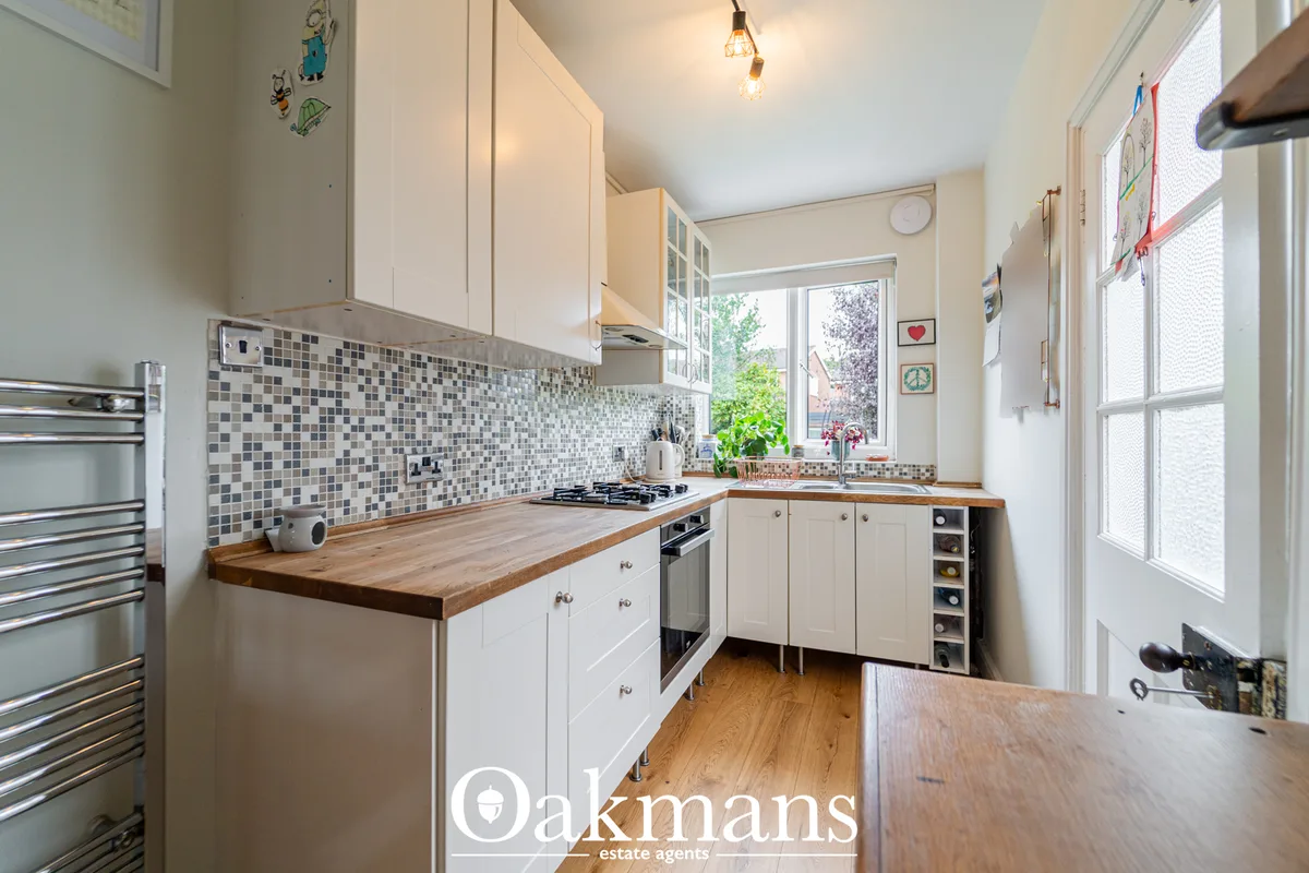 Modern kitchen with white cabinetry, wooden worktops, mosaic tile backsplash, gas cooker, and large windows overlooking 