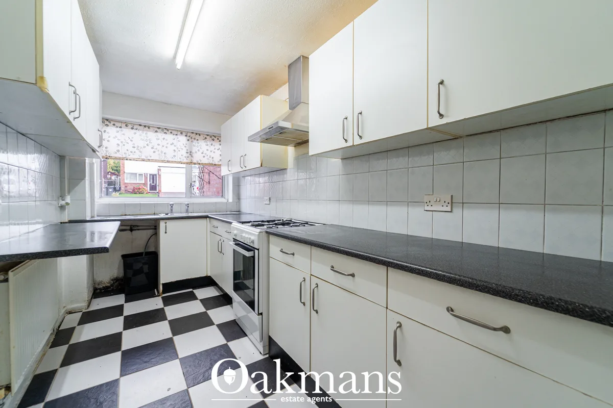 Fitted kitchen with white units, dark granite worktops, gas cooker, black and white tile flooring, grey wall tiles and w