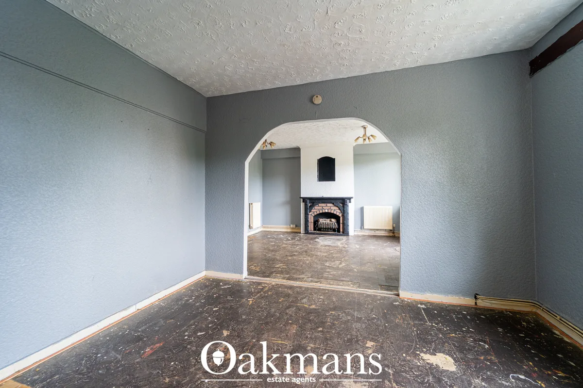 Spacious living room with grey-blue walls, textured white ceiling, dark wooden flooring, arched doorway leading to firep
