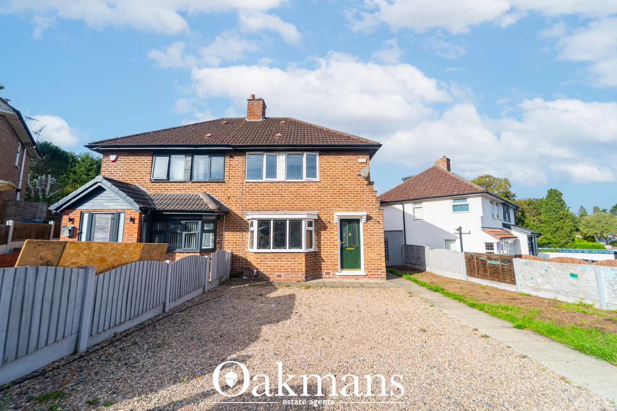 Brick semi-detached house with hipped roof, gravel drive, double garage conversion and adjacent white rendered property 