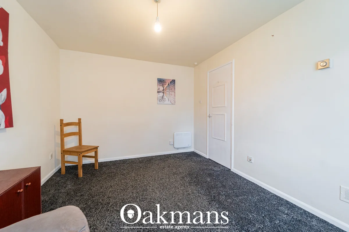 Spacious hallway with cream walls, grey carpet, white door, wooden chair, and pendant light fixture