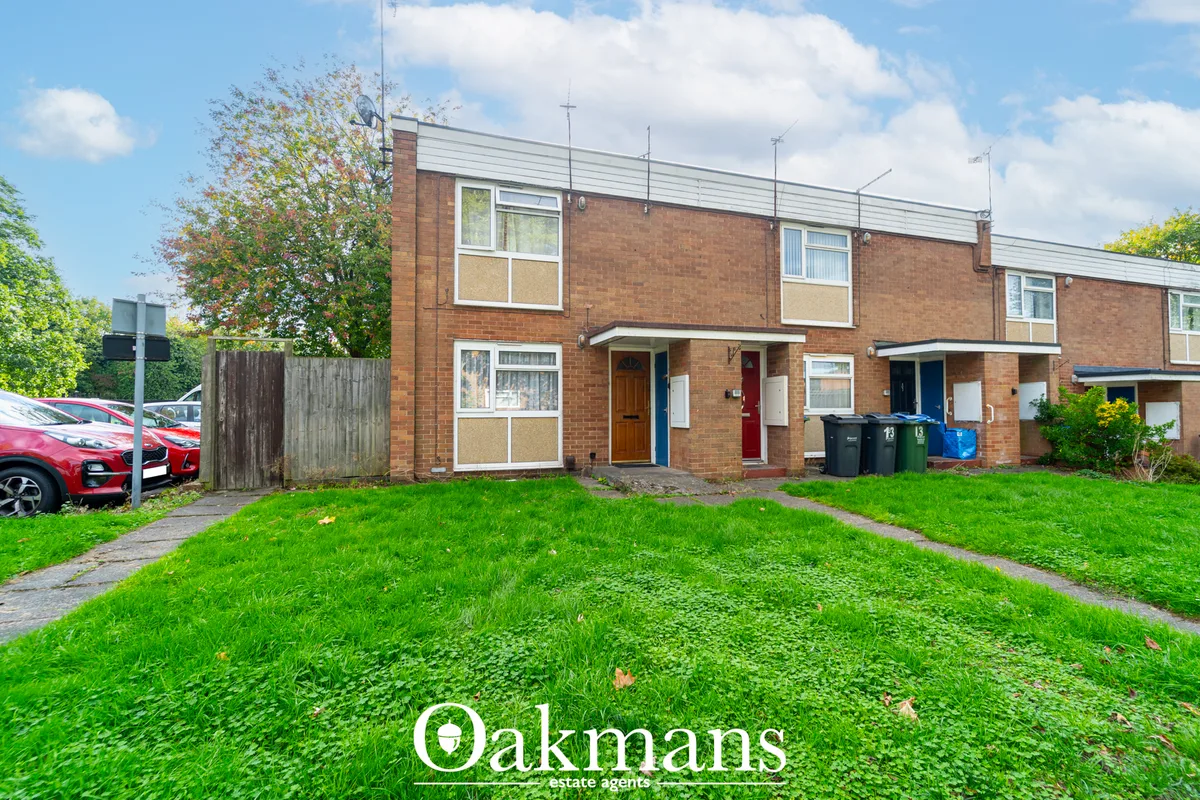 Brick semi-detached house with white metal fascia, gardens and driveway with parked cars, sunny day with clouds
