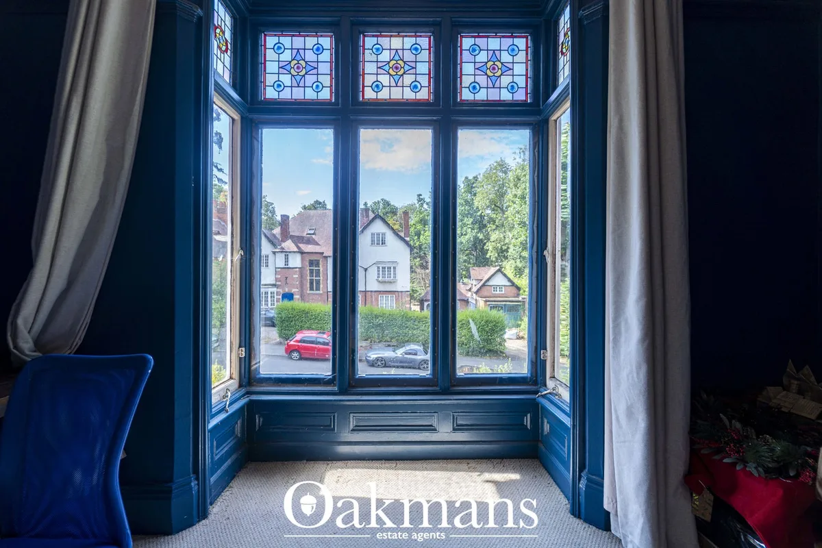 Blue panelled hallway with stained glass window showing suburban street with parked cars and neighbouring properties