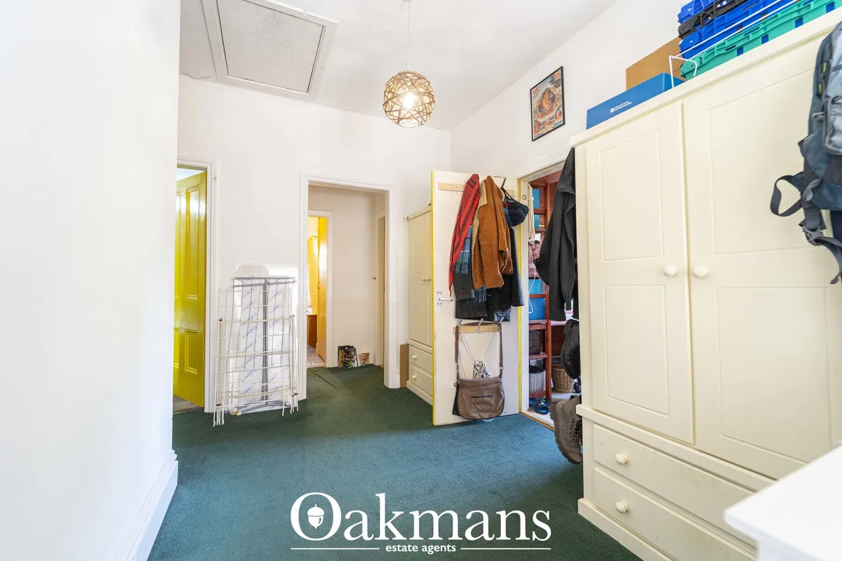 Bright hallway with cream fitted wardrobes, blue-green carpet, white doors, pendant lighting and storage crates
