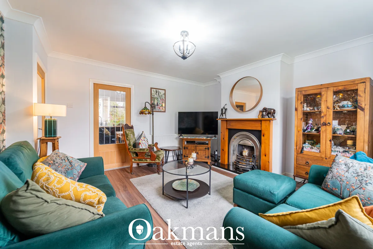 Bright living room with teal upholstered seating, wooden fireplace, round mirror, TV unit, patterned cushions and wooden