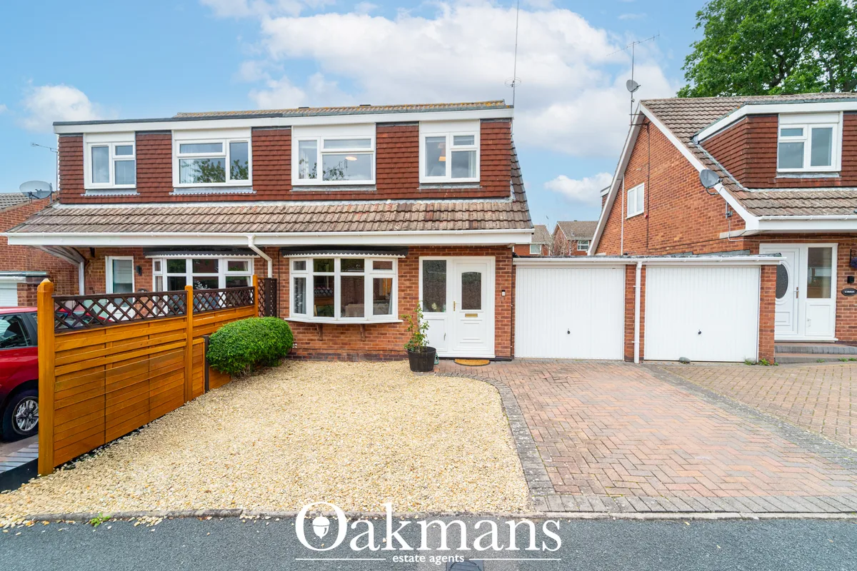 Red brick semi-detached house with white double garage, gravel driveway, wooden gate and brick paved forecourt