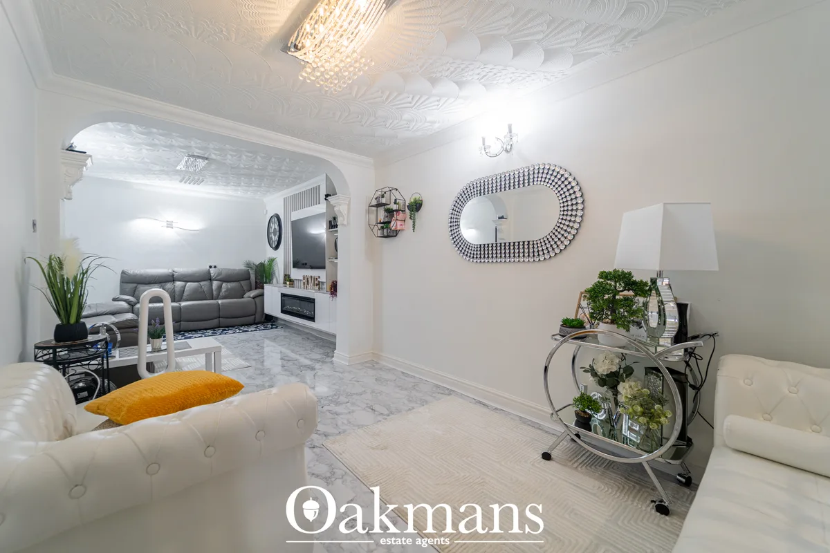 Contemporary living room with cream tufted seating, decorative mirror, marble flooring, potted plants and view through t