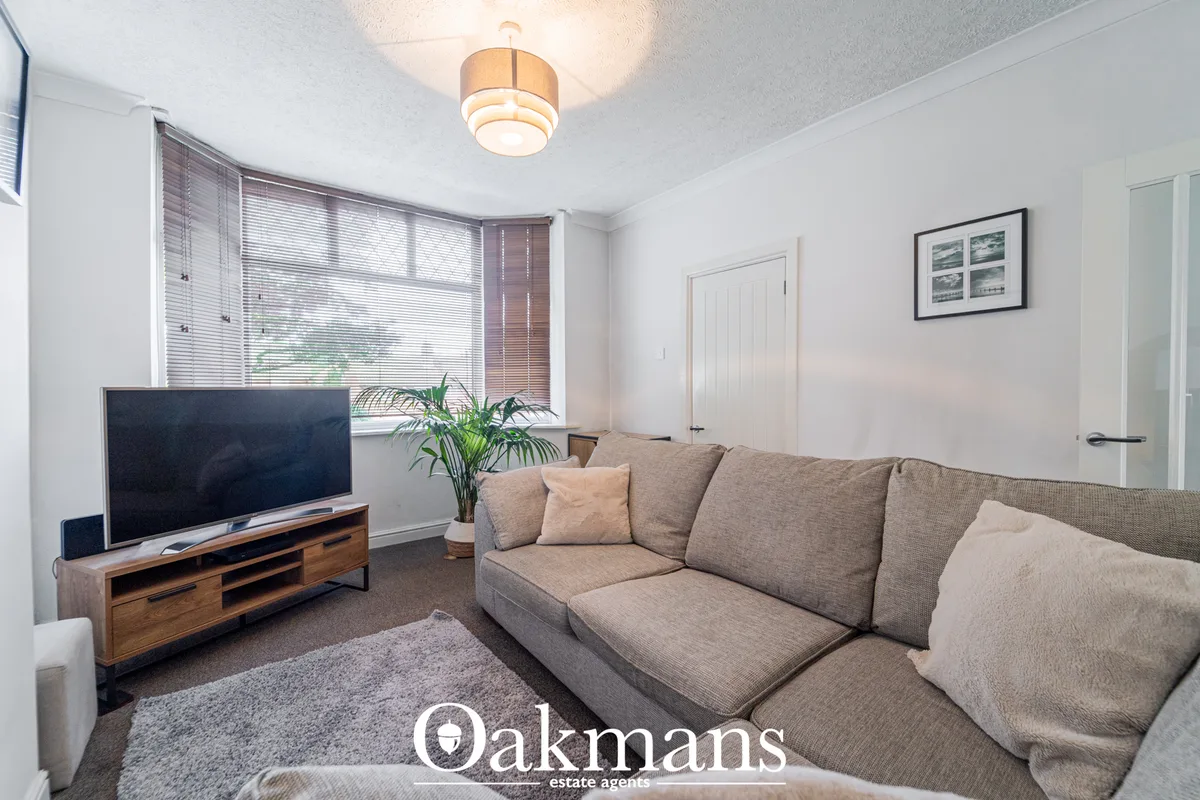 Spacious living room with beige sectional sofa, wooden TV stand, grey rug, large windows with blinds, and modern ceiling