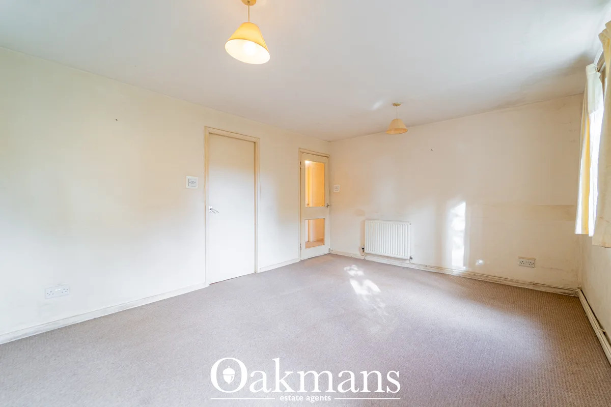 Spacious living room with cream walls, pendant and recessed lighting, radiator, multiple doors and bright natural light 