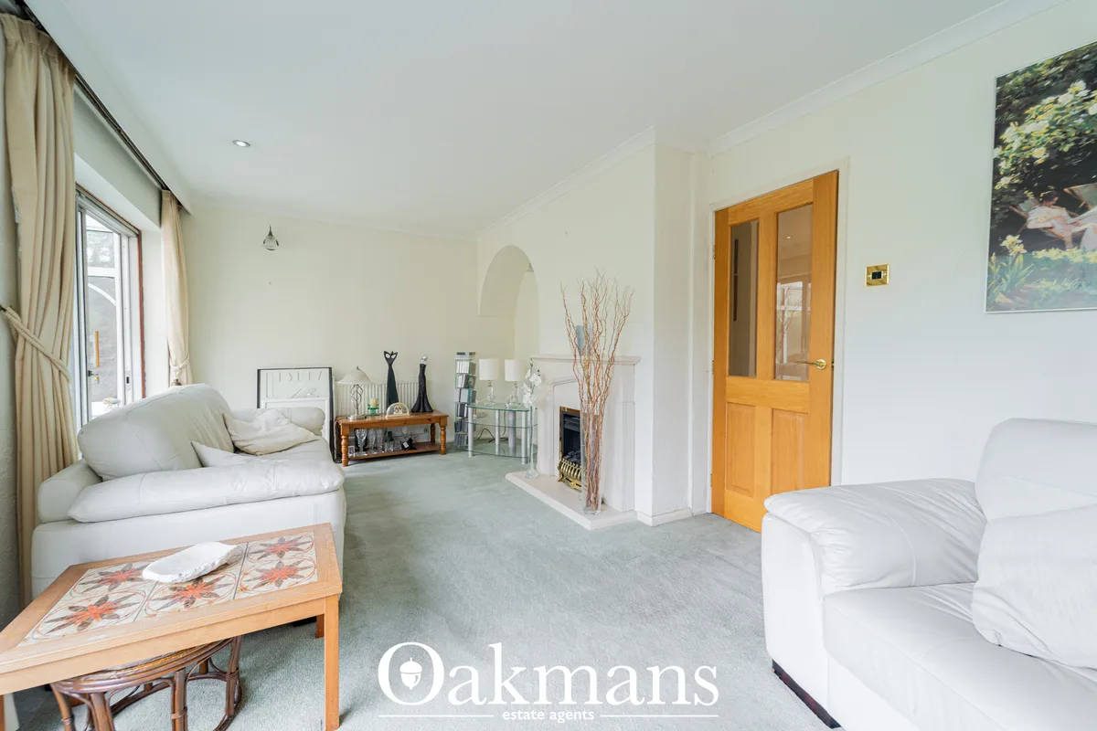 Bright living room with cream sofas, fireplace, wooden door, large window with curtains, and grey carpet