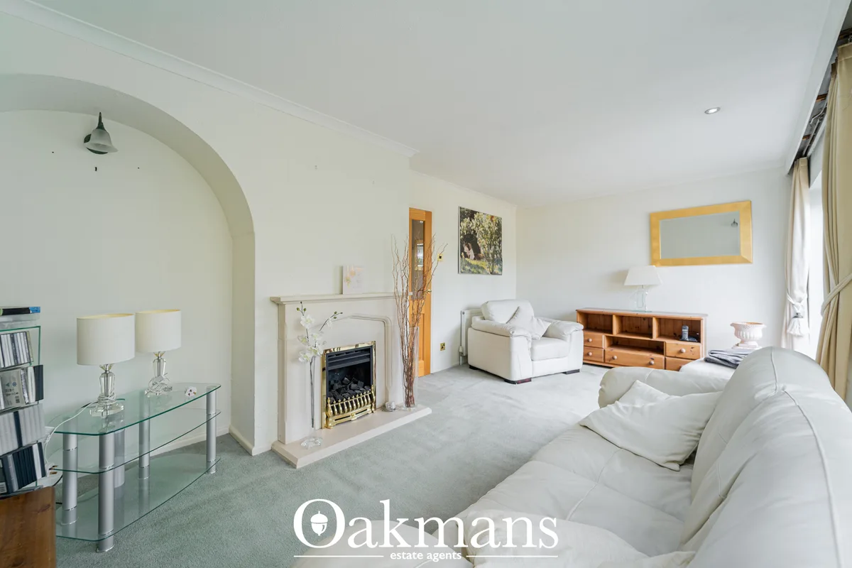 Bright living room with cream sofas, fireplace with gold surround, wooden storage unit, arched ceiling feature, and larg