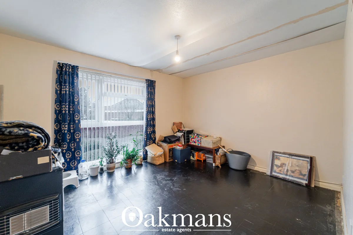 Utility room with dark tiled flooring, cream walls, blue patterned curtains, storage boxes, potted plants and household 