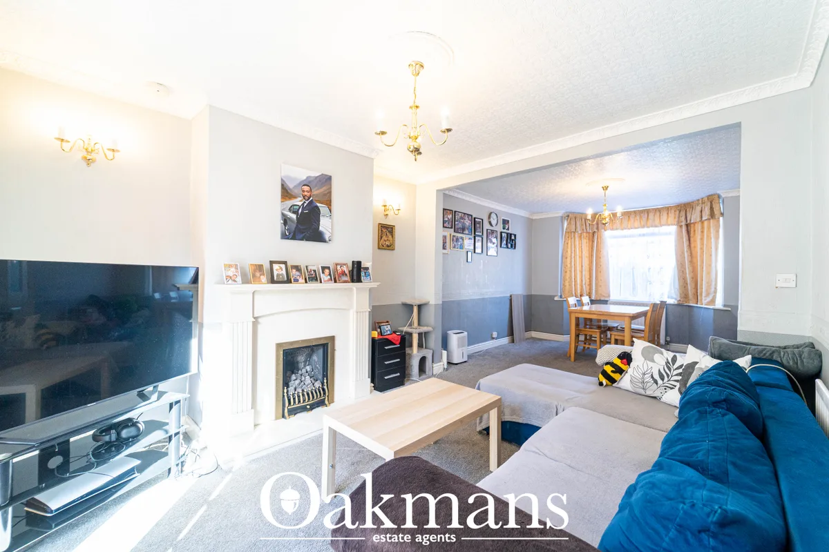 Spacious living room with blue sofa, fireplace with white surround, wall-mounted TV, wooden coffee table, dining area an