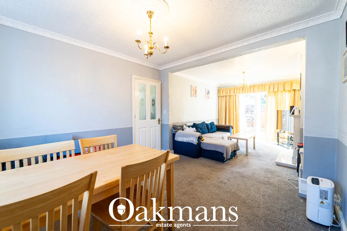 Open-plan living and dining space with wooden dining table, blue sofa, yellow curtains and neutral decor
