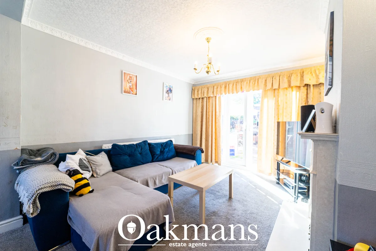 Bright living room with corner sofa, wooden coffee table, wall-mounted TV, yellow curtains and patio doors to garden
