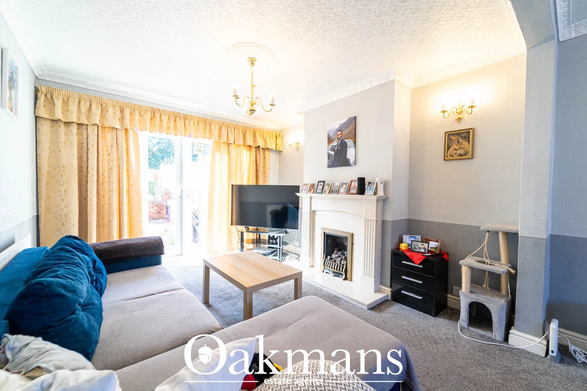 Bright living room with blue sofa, fireplace with mantelpiece, flat-screen TV, wooden coffee table, yellow curtains and 