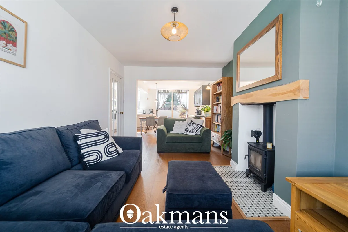 Spacious living room with navy sofa, green armchair, dark stove fireplace, wooden shelving and large mirror with teal ac