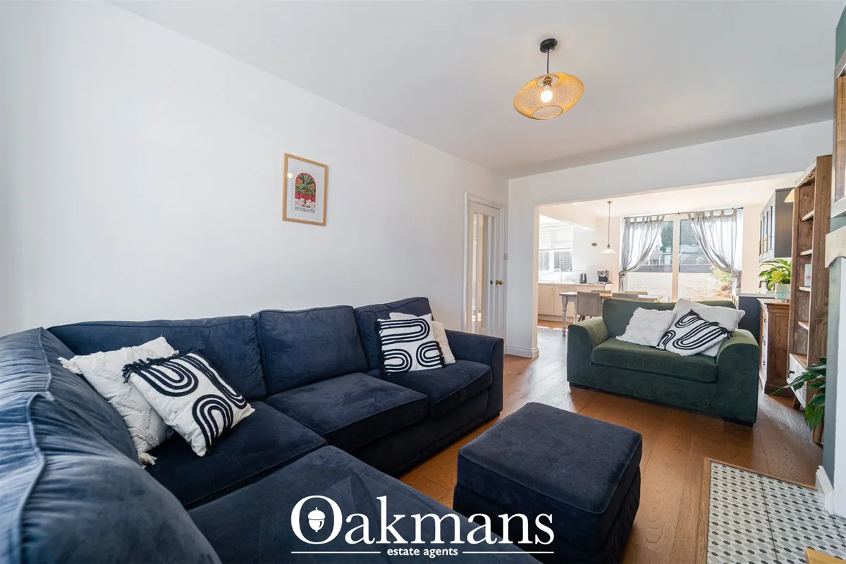 Spacious living room with two navy sofas and armchair, wooden flooring, pendant lighting, white walls and open-plan view