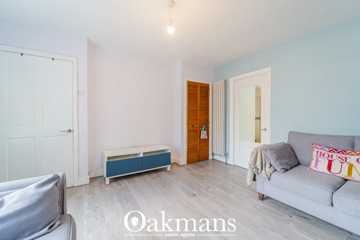 Bright bedroom with grey sofa, wooden storage unit, white doors, pendant light and light wood flooring