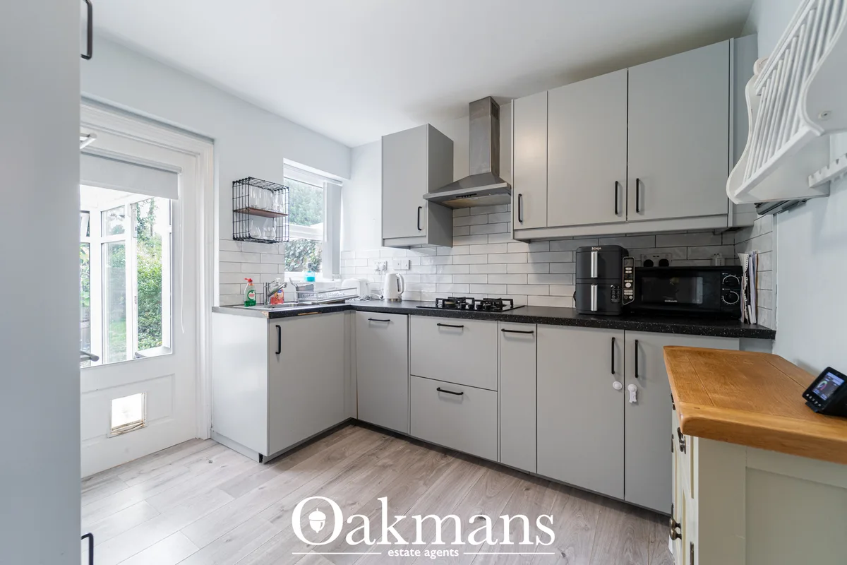 Modern fitted kitchen with grey units, black granite worktops, white subway tile splashback, gas hob, integrated applian