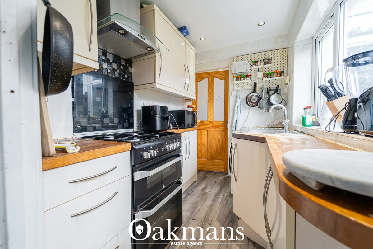 Modern fitted kitchen with white units, wooden worktops, black double oven, gas hob, black tile splashback and breakfast