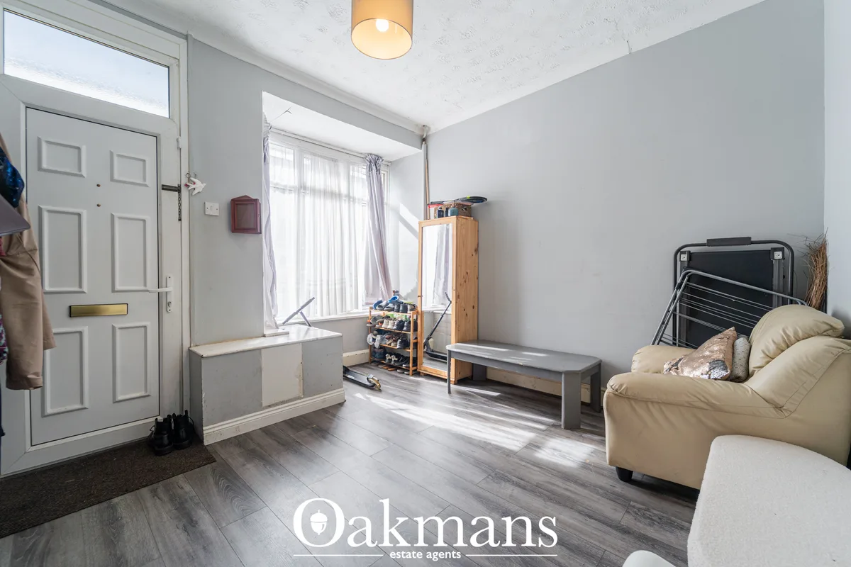 Bright entrance hallway with light wood flooring, white panelled door, window seat with radiator, wooden storage unit, b