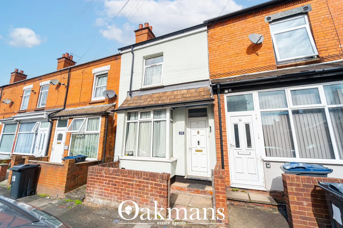 Terrace of red brick Victorian terraced houses with white-framed doors and windows, satellite dishes, blue bins, clear s