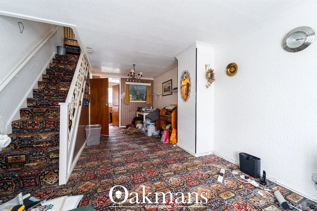 Entrance hallway with ornate patterned carpet, white walls, wooden staircase with patterned runner, wooden doors, wall c