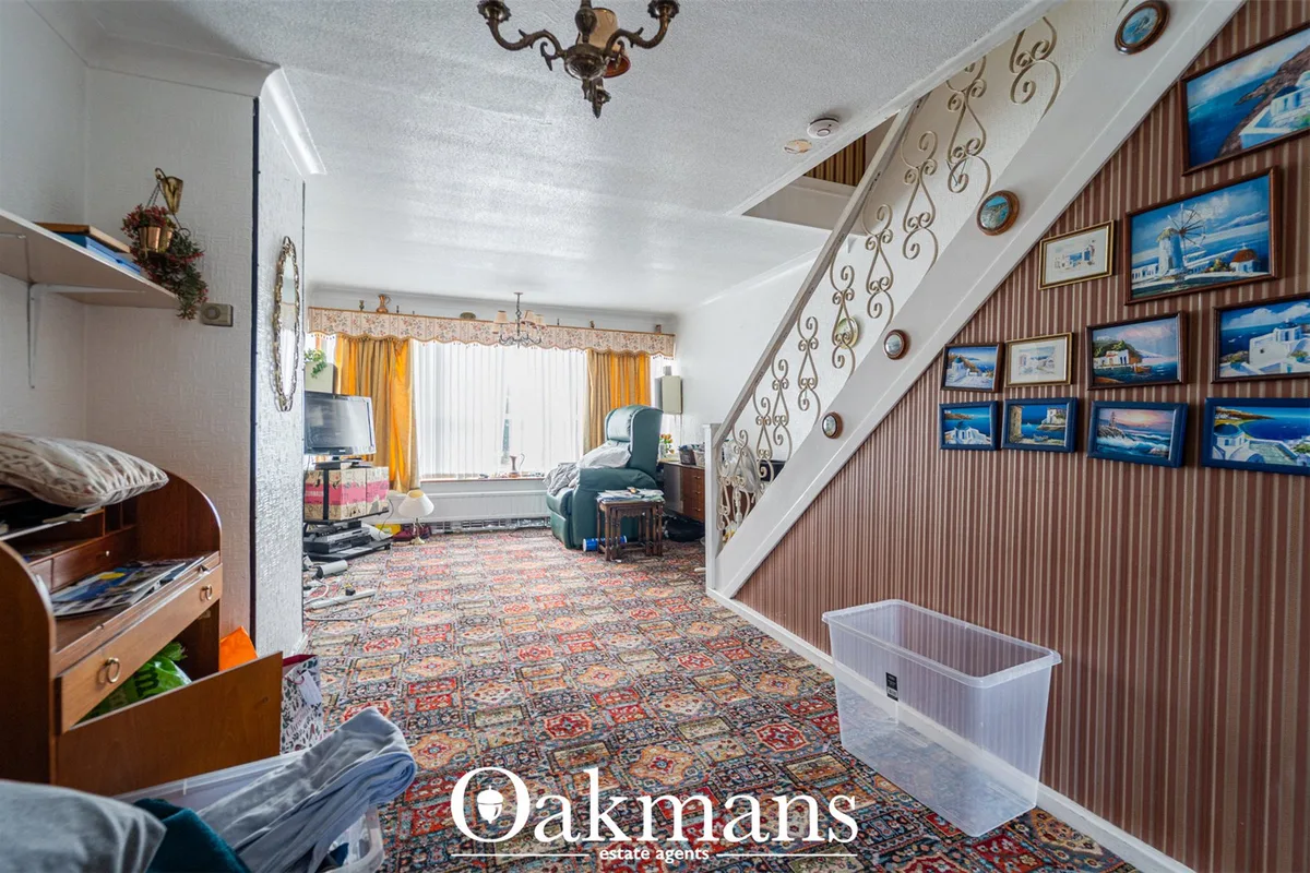 Spacious hallway with ornate staircase, patterned carpet, decorated walls with coastal artwork, and white ceiling with p
