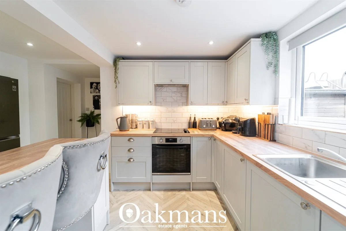 Modern fitted kitchen with cream cabinetry, wooden worktops, white subway tile splashback, stainless steel oven, breakfa