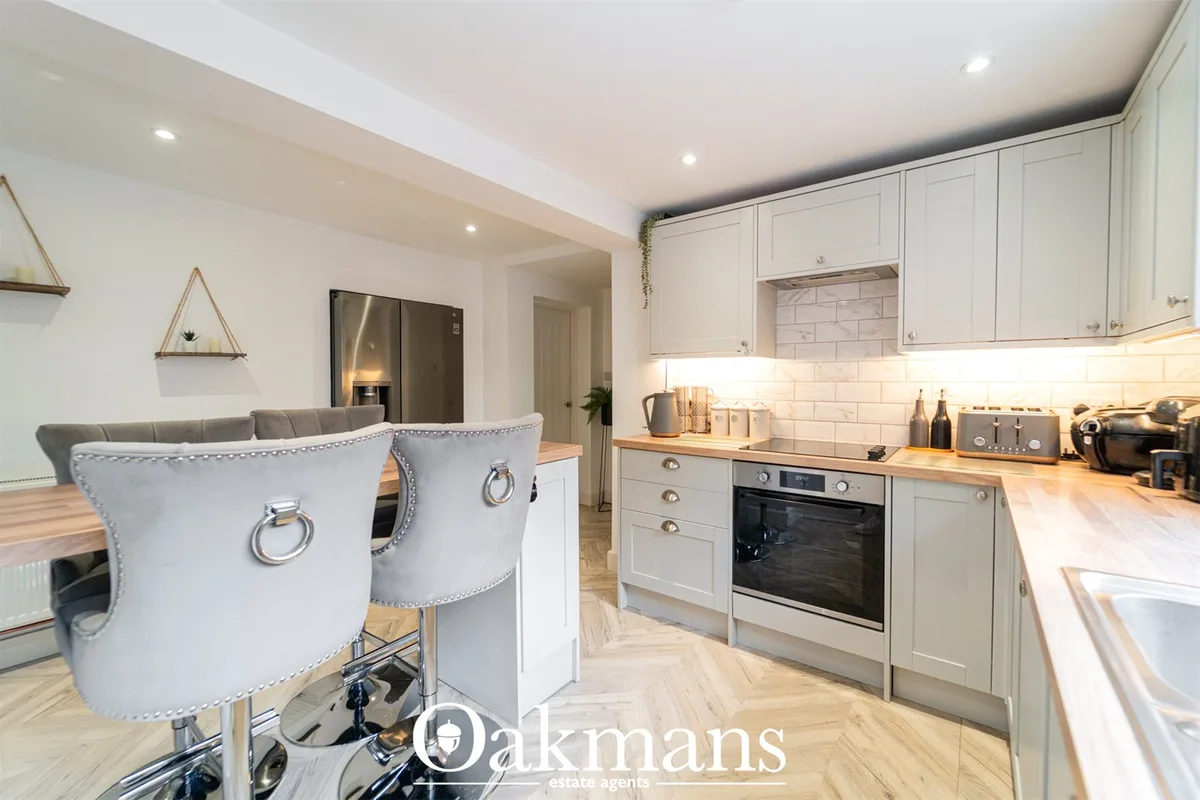 Modern fitted kitchen with white cabinetry, wooden worktops, stainless steel appliances, white subway tile splashback, L