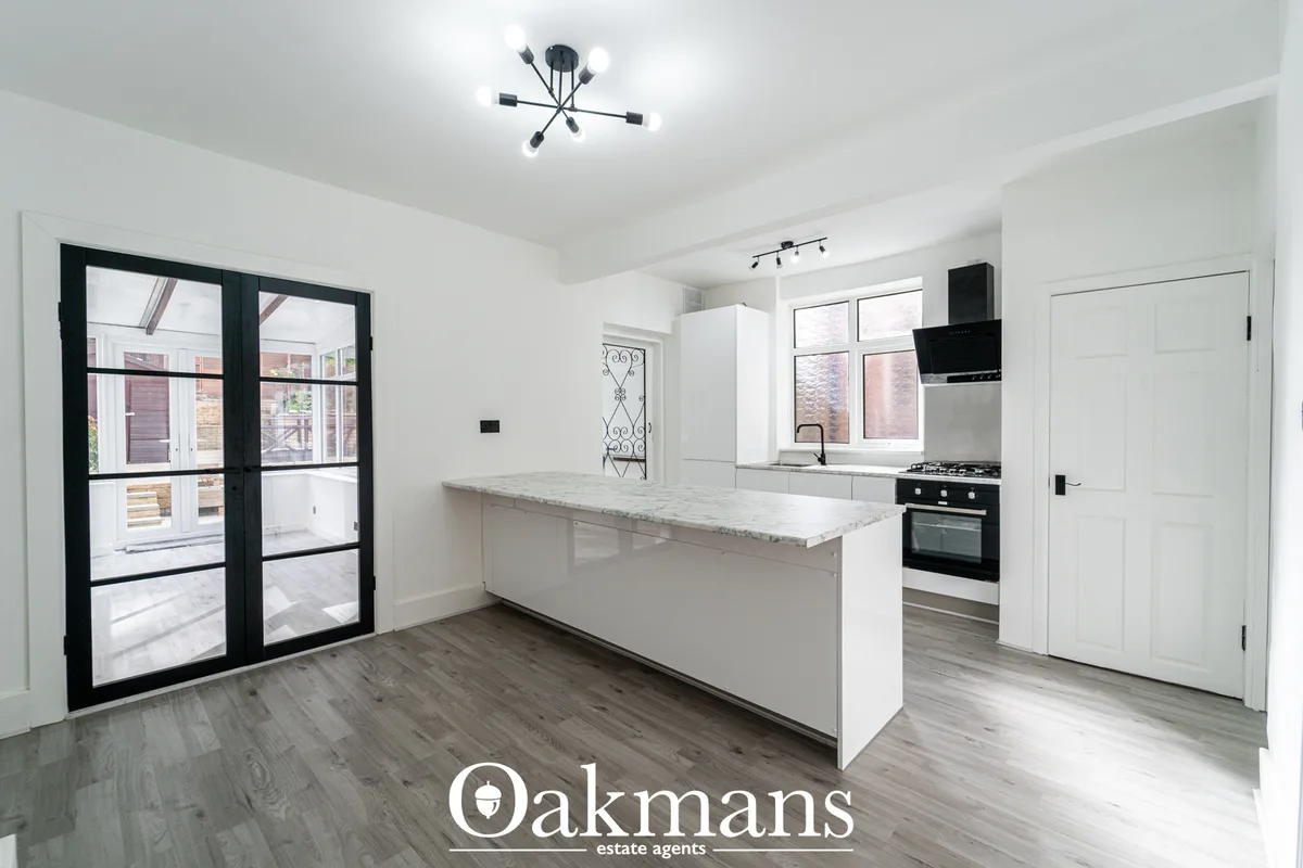 Modern open-plan kitchen with white fitted units, marble worktops, breakfast bar island, black range cooker, and french 