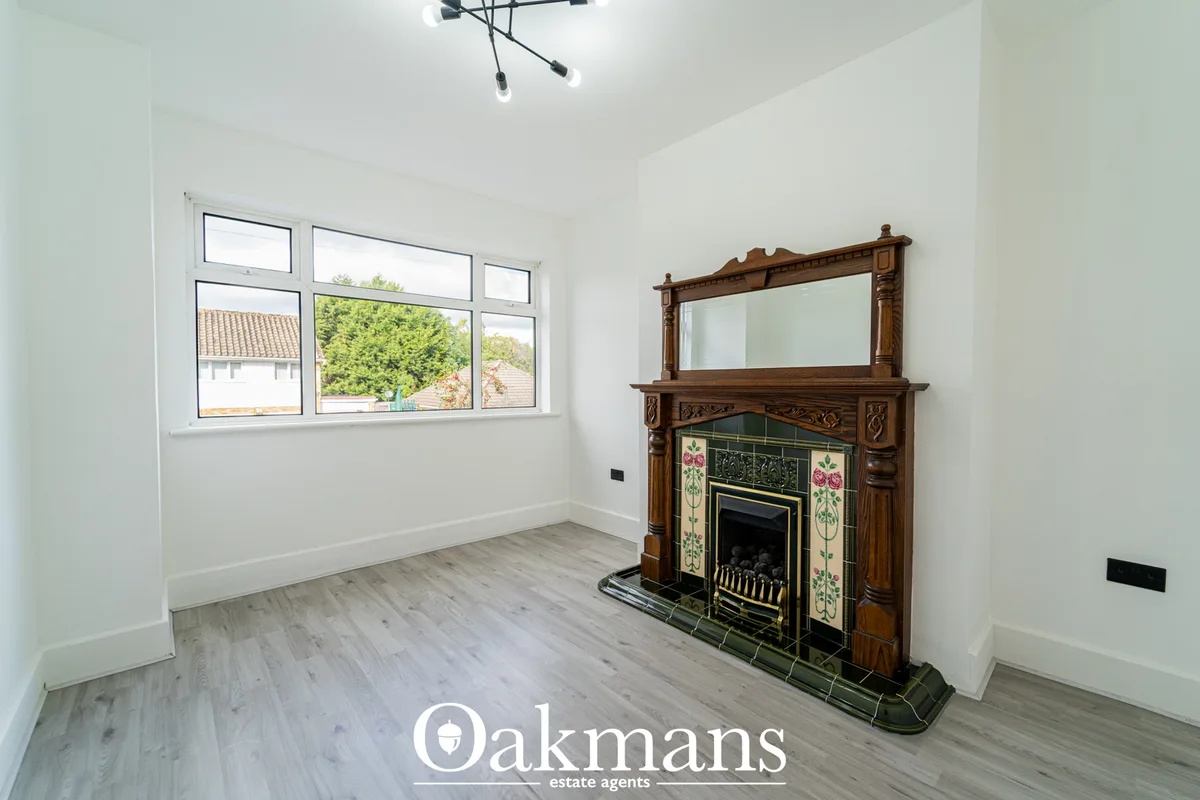 Bright living room with bay windows, ornate wooden fireplace with decorative tile surround, wooden flooring, and modern 