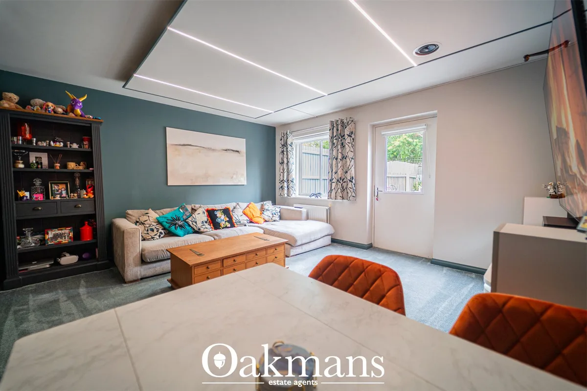 Contemporary living room with teal accent wall, cream L-shaped sofa, wooden coffee table, orange dining chairs, and mode