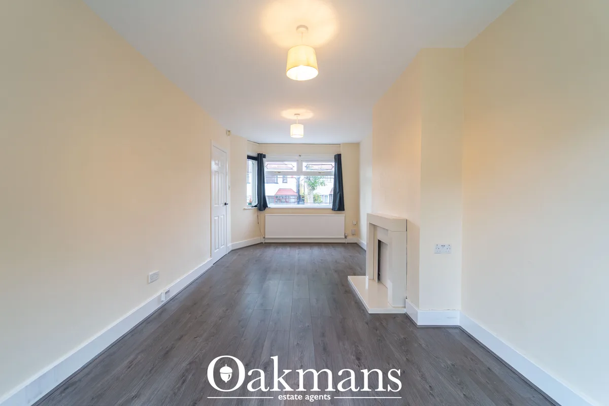 Bright hallway with dark wood flooring, cream walls, ceiling lights, window with blue curtains, built-in storage cupboar