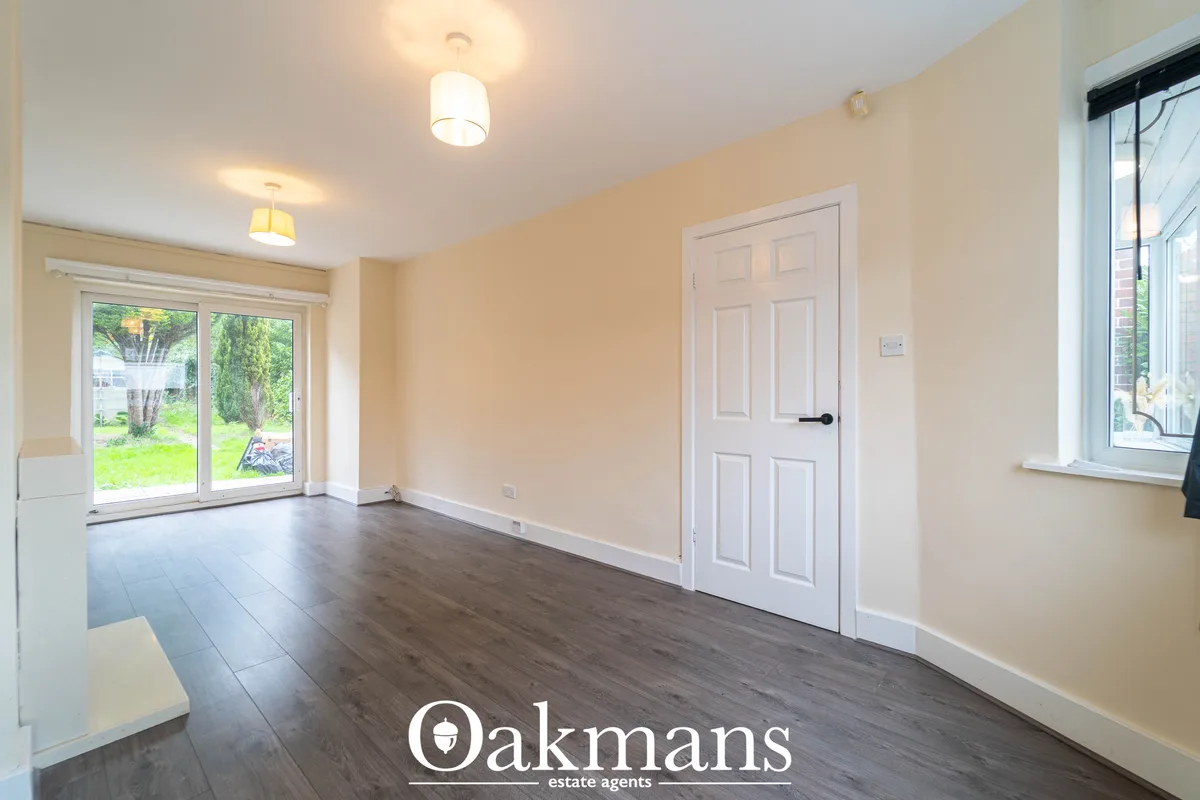 Bright entrance hallway with cream walls, dark wood-effect flooring, white six-panel door, dual ceiling lights and patio