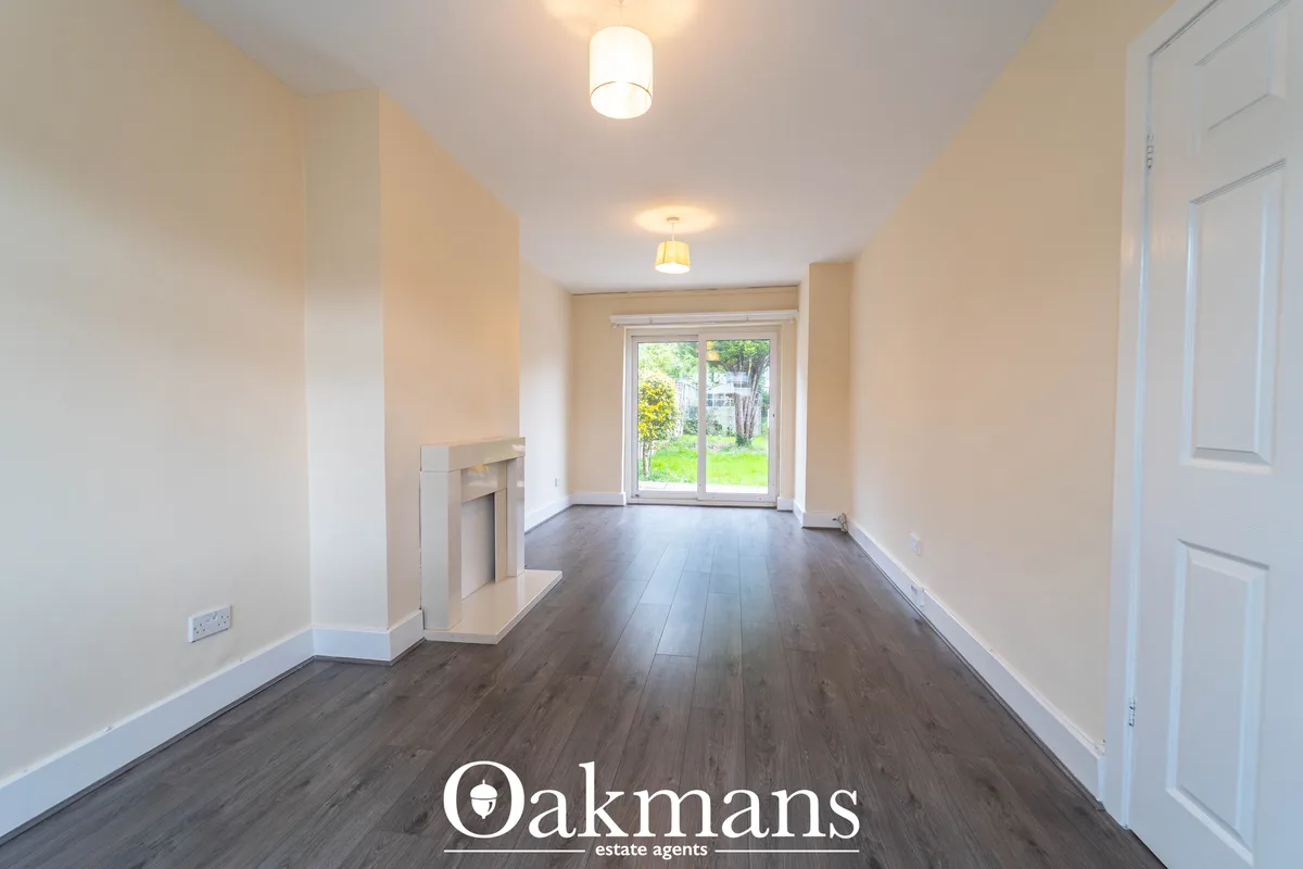 Bright hallway with cream walls, dark wood flooring, fireplace surround, ceiling lights, white doors, and glass doors op