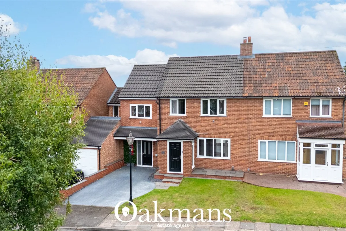 Two-storey brick semi-detached house with tiled roof, driveway, garden, and neighboring properties visible