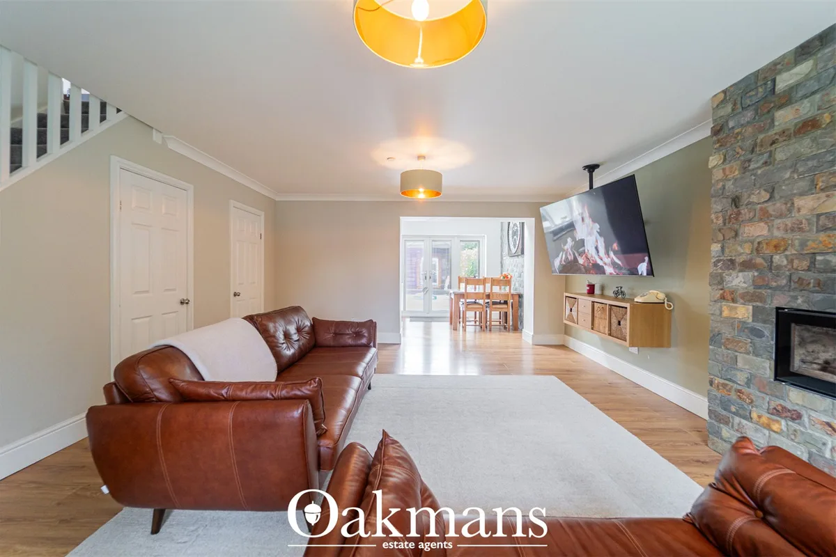 Spacious living room with cognac leather seating, exposed brick fireplace, mounted TV, wood flooring and yellow pendant 
