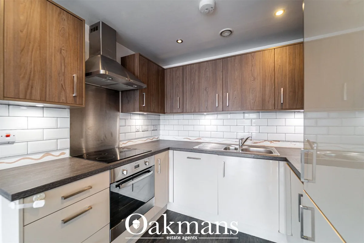 Modern fitted kitchen with walnut and white cabinetry, dark granite worktops, stainless steel range hood, electric oven,