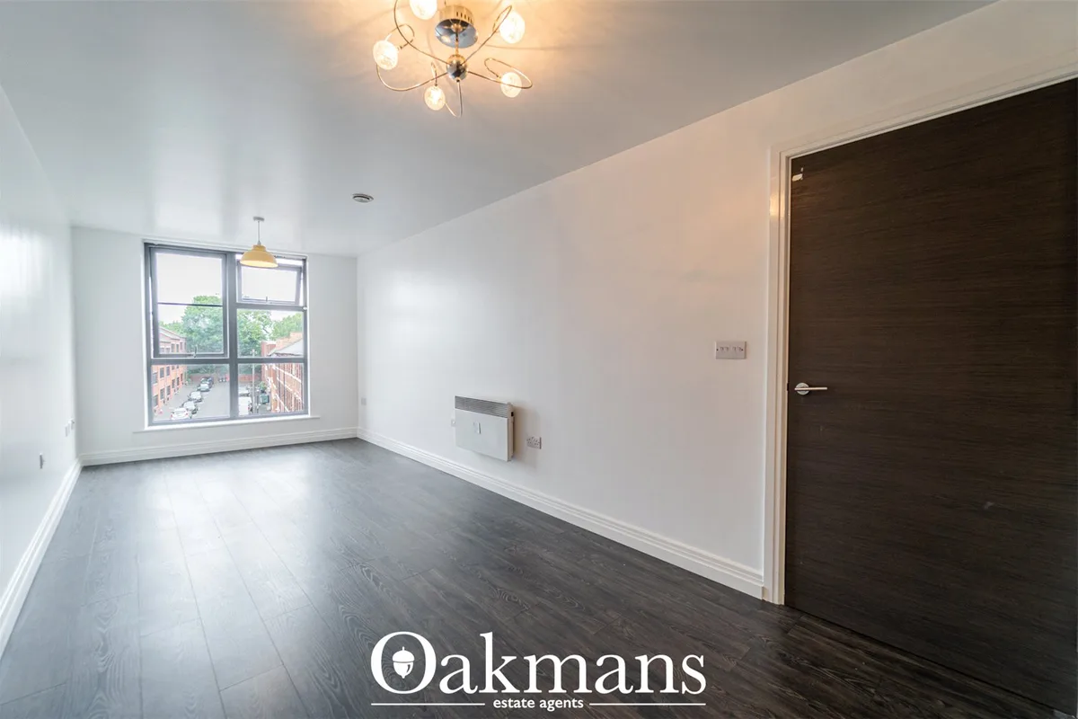 Bright modern hallway with dark wood flooring, white walls, large window overlooking street, decorative ceiling light an