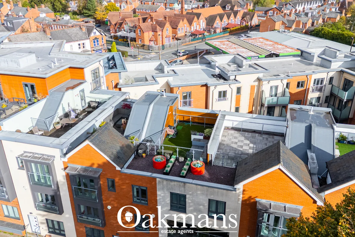 Aerial drone photograph of modern residential development with orange and white brick houses, rooftop gardens, and surro