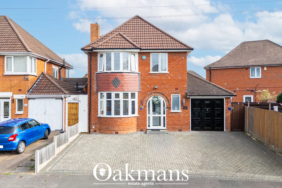 Red brick detached house with pitched tile roof, arched entrance door, bay windows, block paved driveway and blue car pa