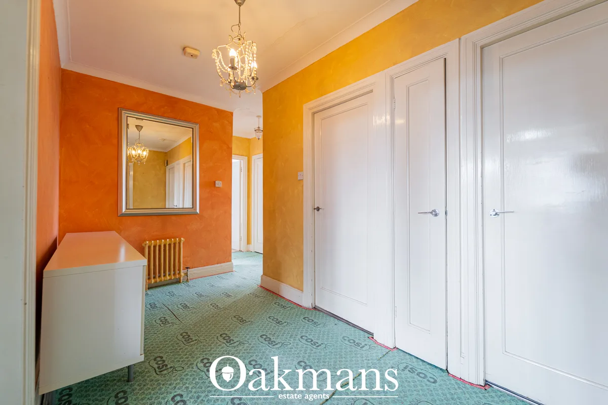 Bright hallway with orange and cream walls, white panelled doors, patterned carpet, pendant light and radiator